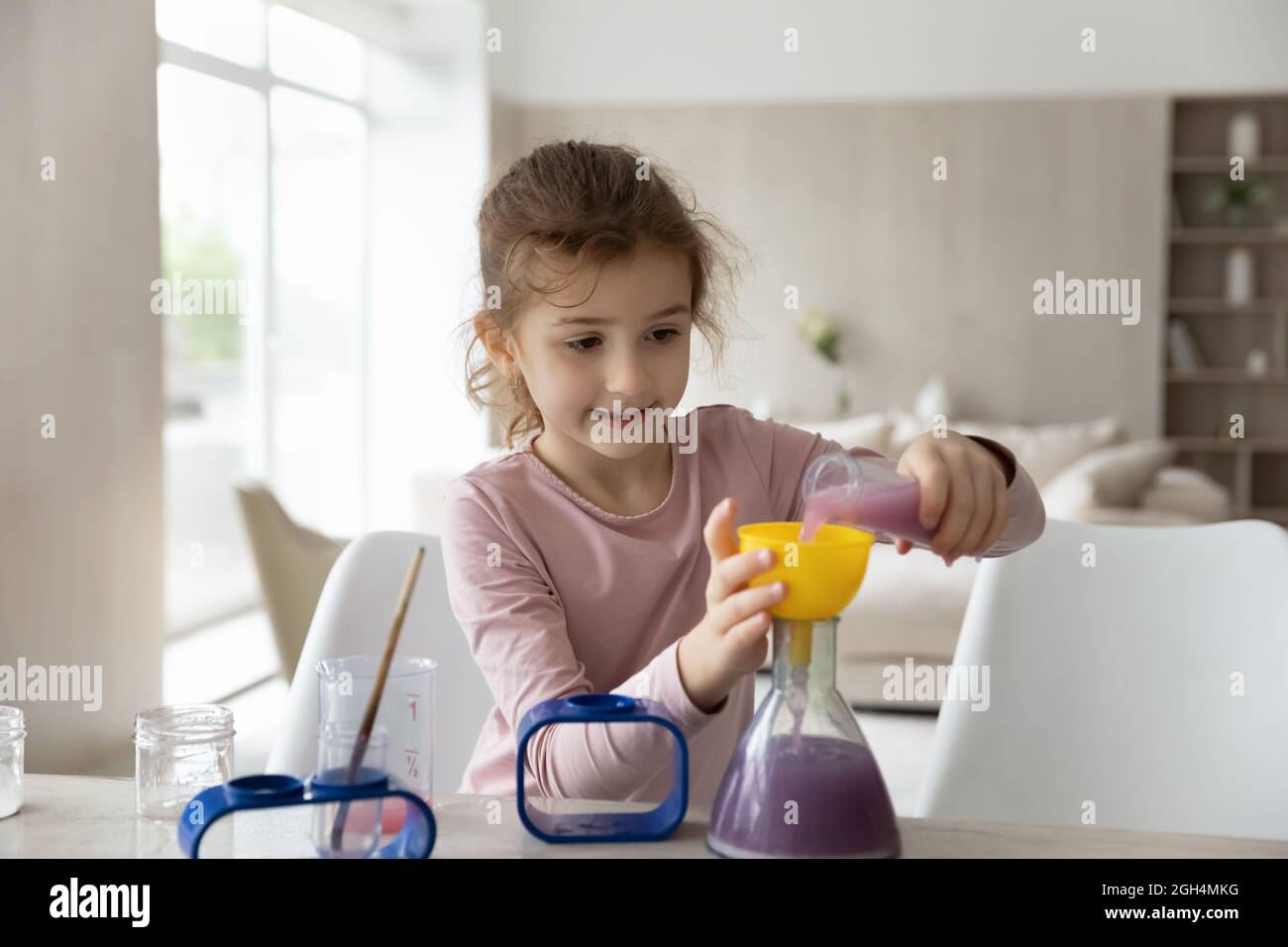 Happy smart kid girl making experiments at home. Stock Photo