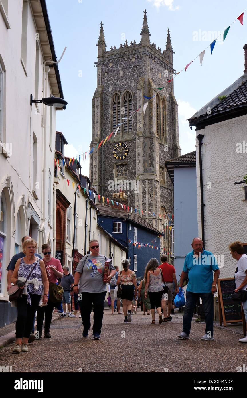 People walking down a cobbled street with St. Peter's & Paul's church tower in the background. Stock Photo