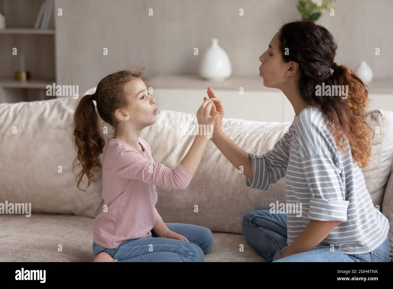 Young mother teaching little kid daughter correct pronunciation. Stock Photo