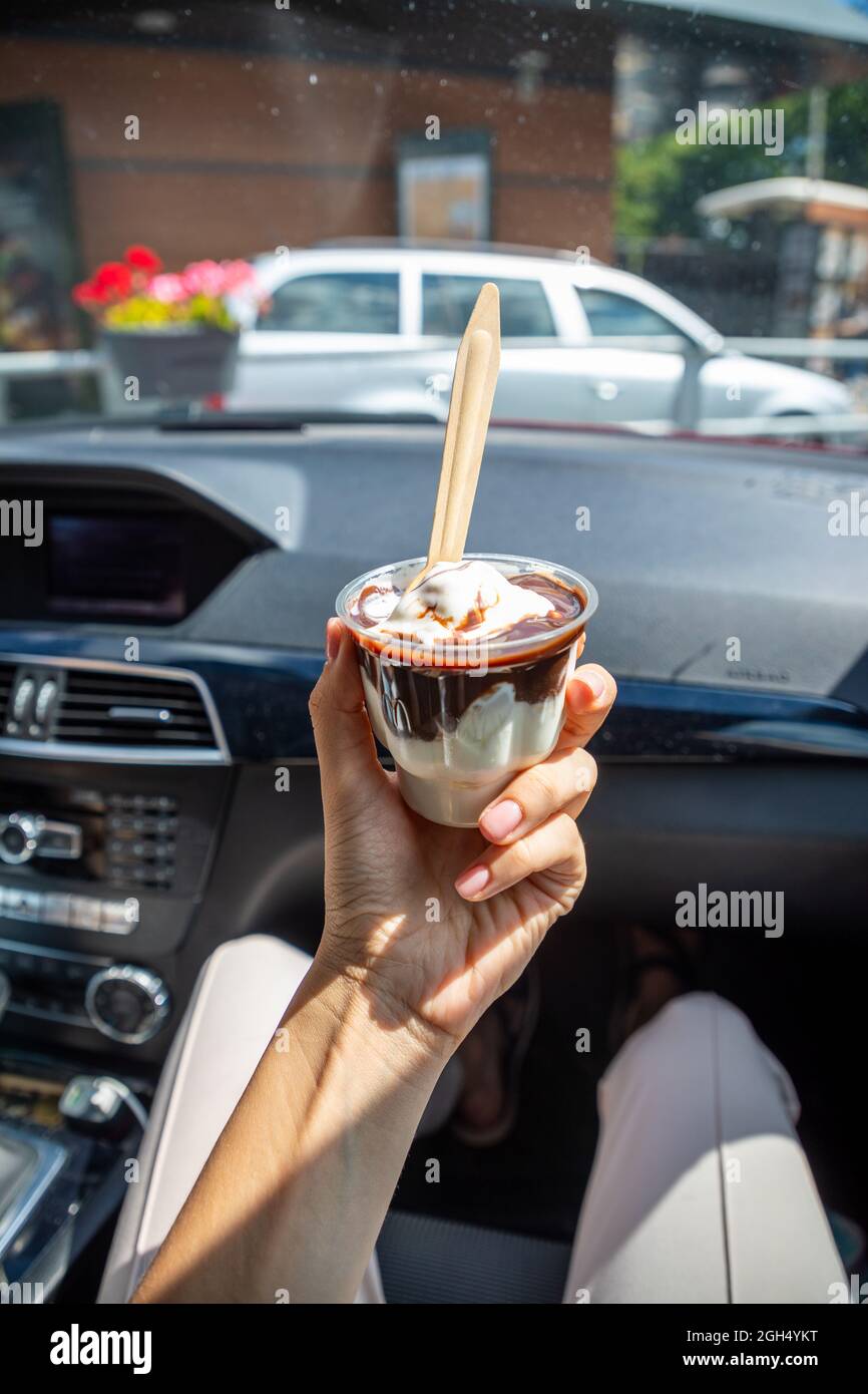 Woman holding the McDonalds McFlurry Ice Cream with chocolate in a car after drive thru. Drive thru concept Stock Photo