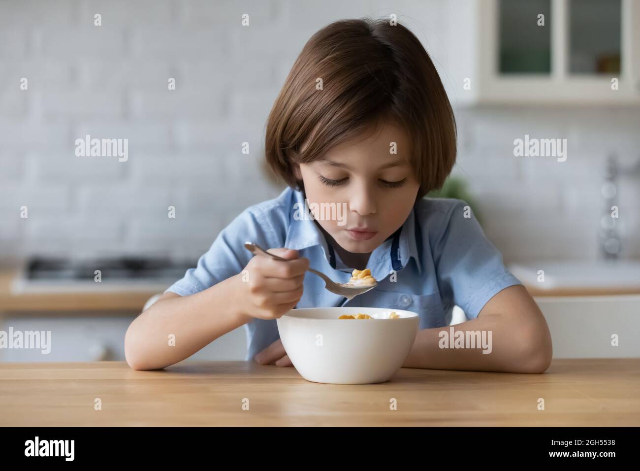 Happy little adorable child boy eating fast dry breakfast. Stock Photo