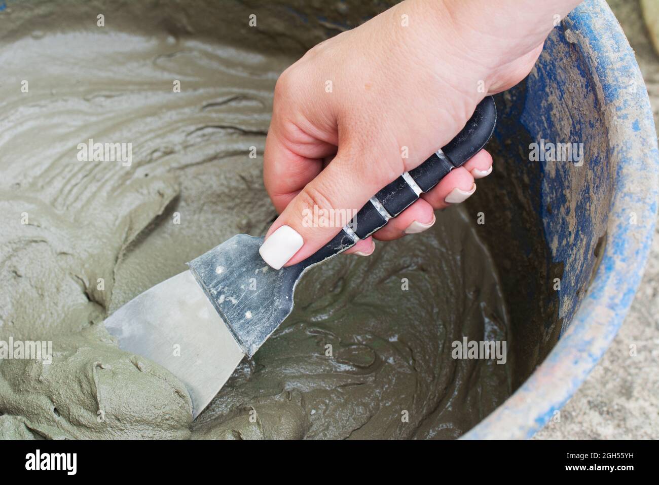 Woman hand plastering wall with trowel. Cement mix process