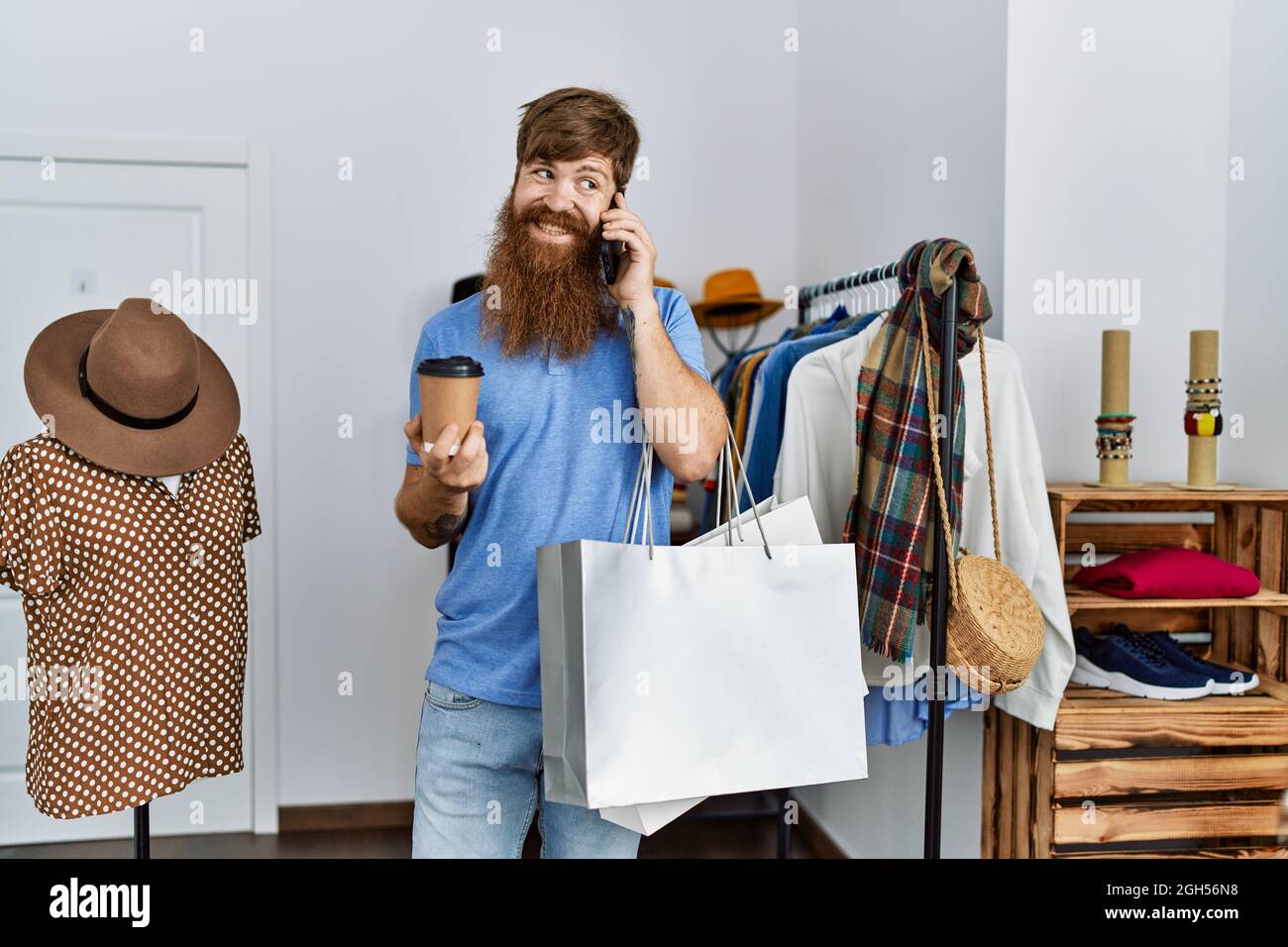 Young redhead customer man talking on the smartphone and drinking