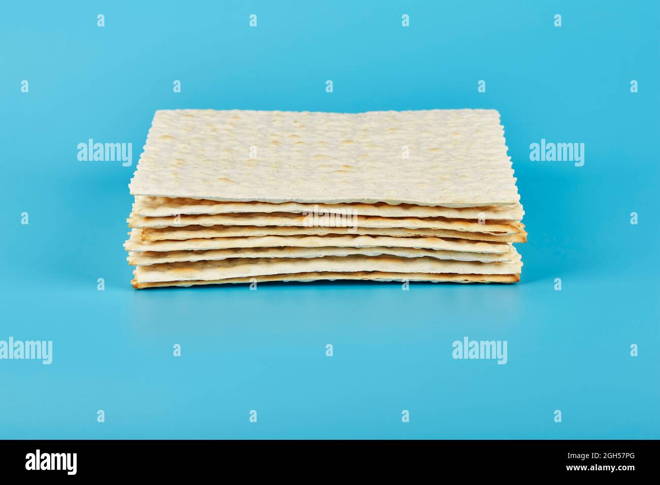 Traditional Jewish matzah lies in an even stack on a blue background. Matzoh for the Jewish