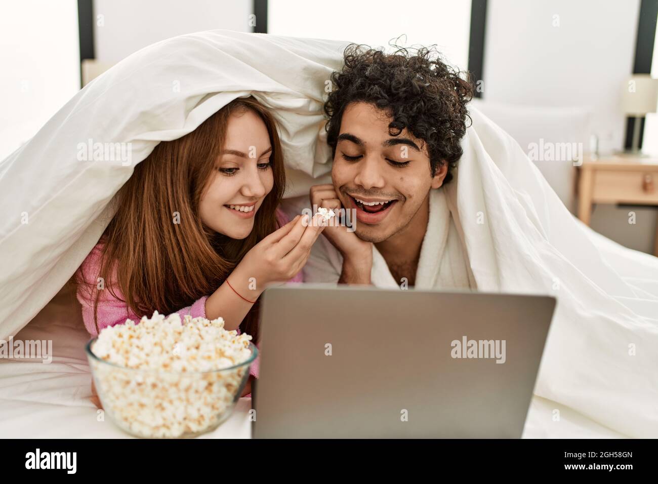 Young couple watching movie lying on the bed at bedroom Stock Photo - Alamy