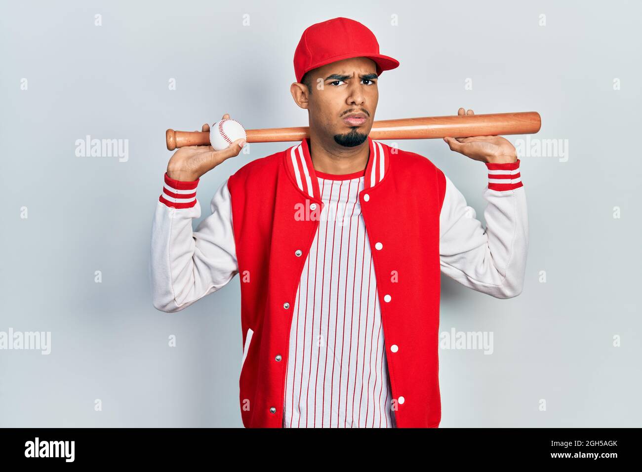 Young african american man playing baseball holding bat and ball in