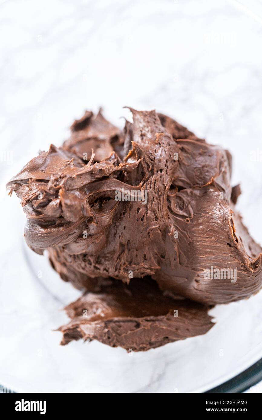 Mixing storebought chocolate frosting in a mixing glass bowl with a