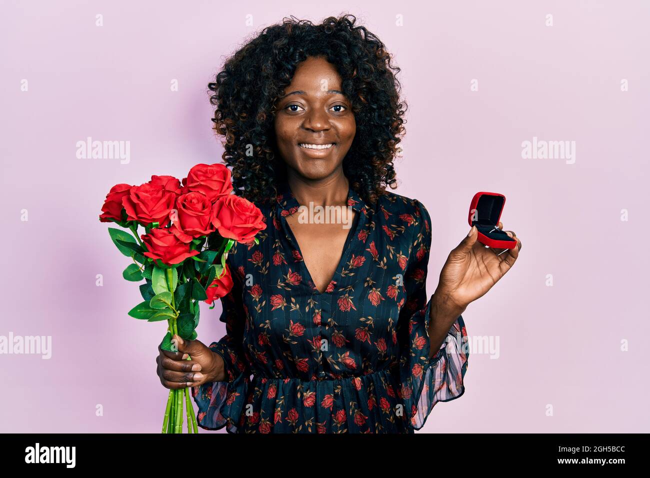 Young african american woman holding bouquet of flowers and engagement ...