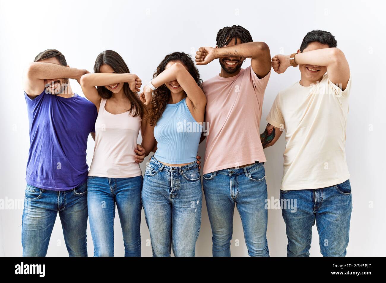 Group of young people standing together over isolated background smiling  cheerful playing peek a boo with hands showing face. surprised and exited  Stock Photo - Alamy