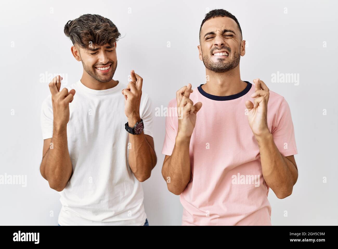 Young gay couple standing over isolated background gesturing finger crossed  smiling with hope and eyes closed. luck and superstitious concept Stock  Photo - Alamy