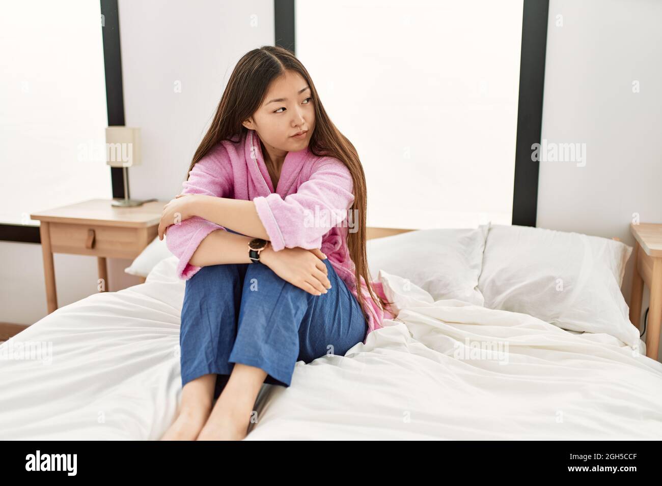 Young chinese girl smiling happy sitting on the bed at bedroom Stock ...