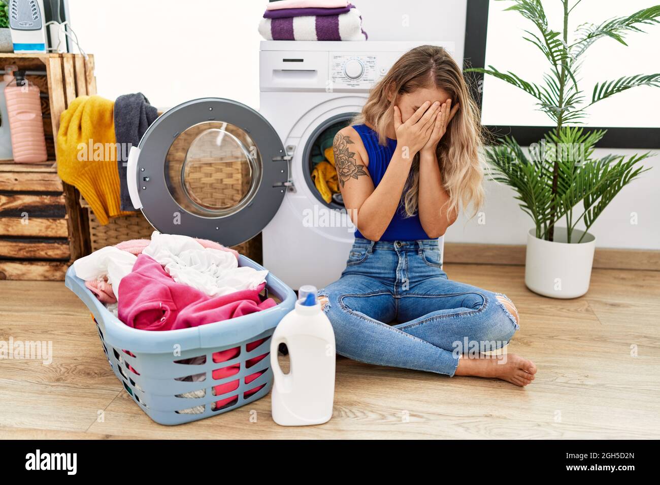 Young beautiful woman doing laundry sitting by wicker basket with sad  expression covering face with hands while crying. depression concept Stock  Photo - Alamy