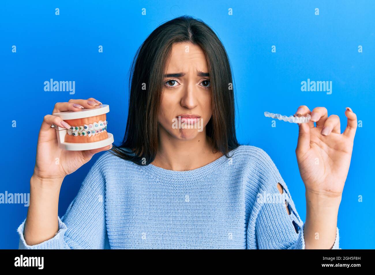 Young hispanic girl holding invisible aligner orthodontic and braces