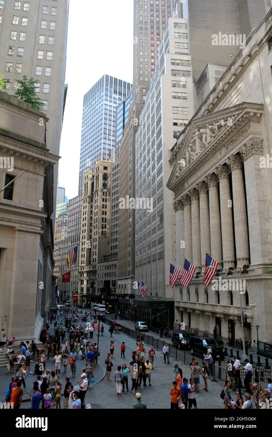 NEW YORK, USA - August 5, 2014: From Federal Hall, pedestrians walk along Broad Street past the New York Stock Exchange. The Exchange building was bui Stock Photo