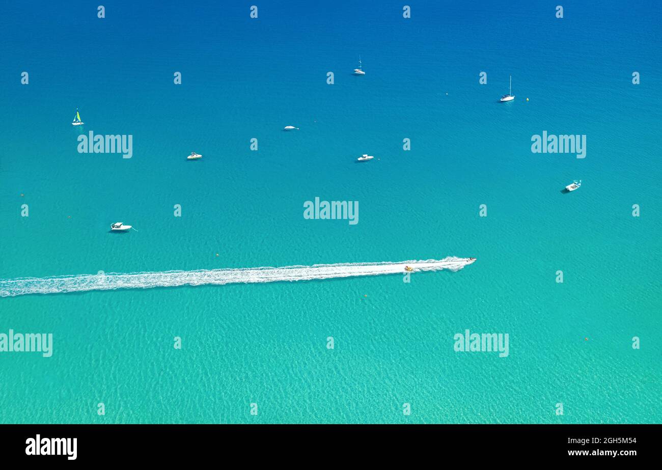 Speedboat and wave slider leaving trail on water, with other boats and sea as background with copy space. Aerial seascape Stock Photo