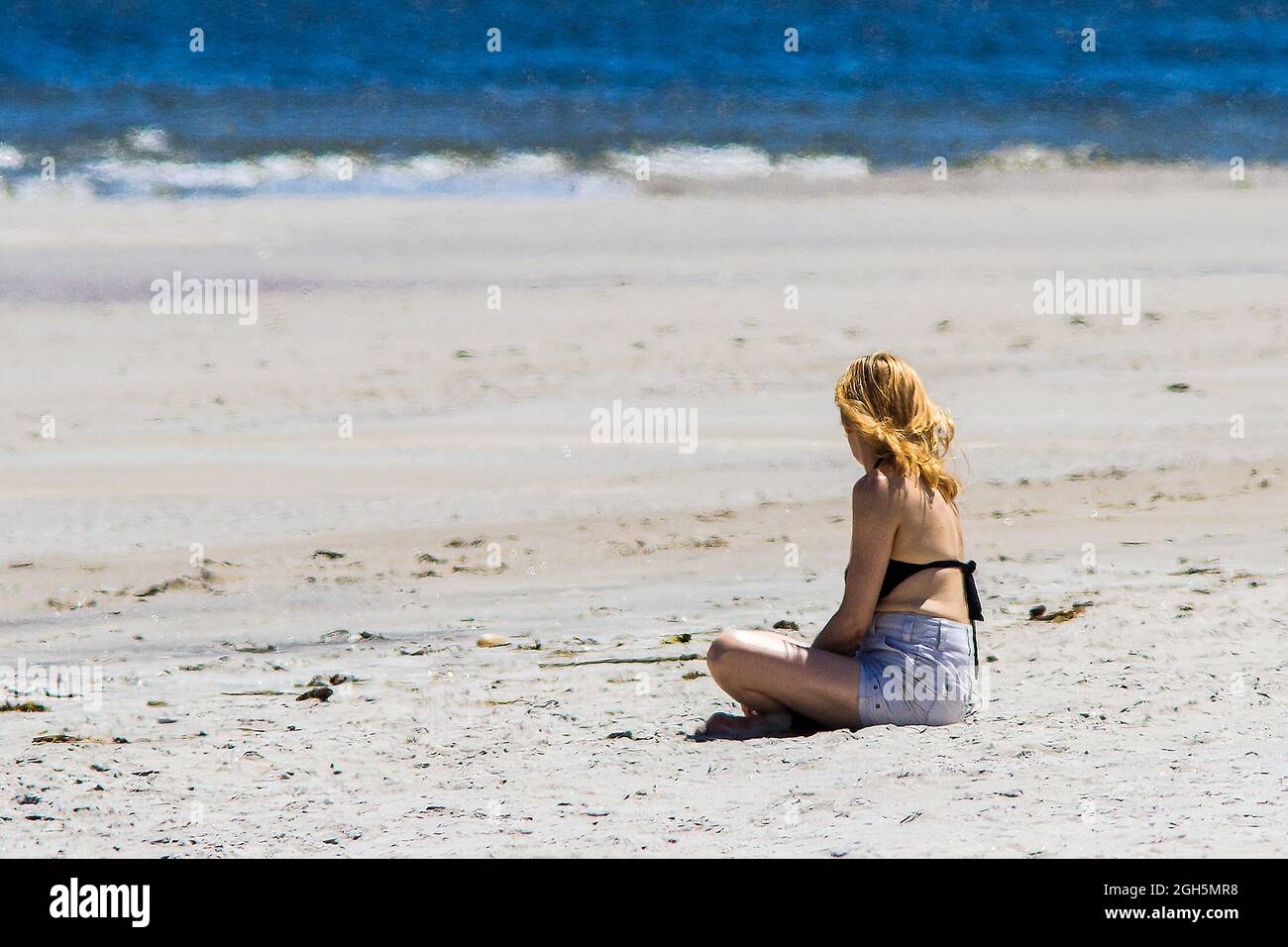 A young woman sitting alone on the beach Stock Photo - Alamy