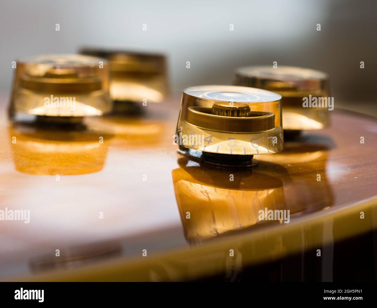 A close view of a retro electric guitar volume knob.A reflection of it can be seen in the body