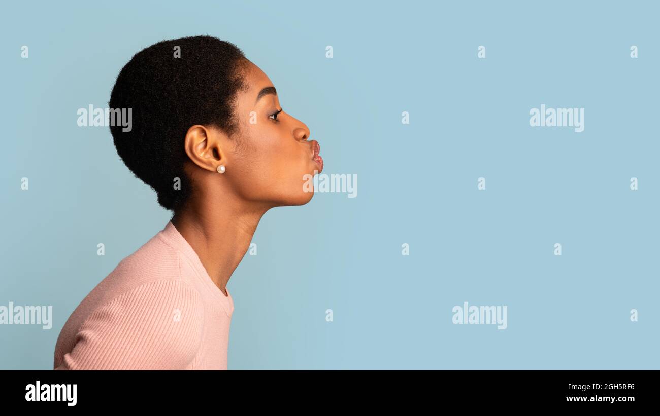 Side View Of Young Black Female Pouting Lips Over Blue Studio