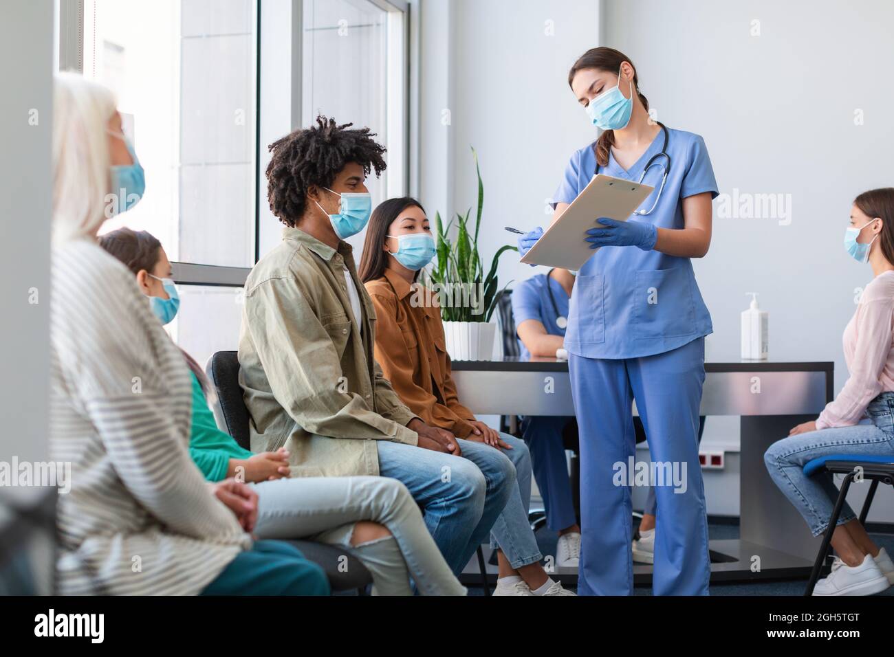 Patients Waiting For Covid-19 Vaccination Sitting In Line In Clinic Stock Photo