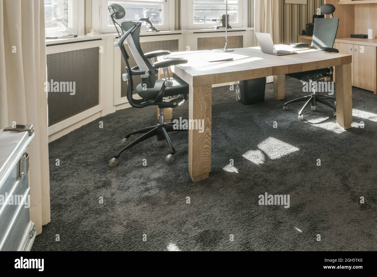 Wooden table with laptop and comfortable armchairs placed near ...