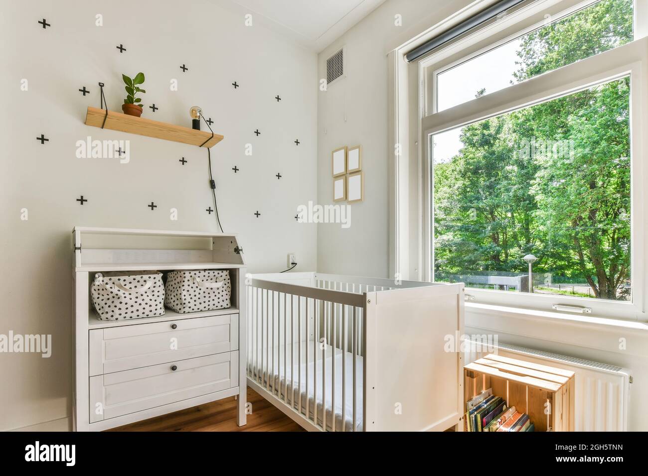White crib placed between and bookshelf near window in sunlit