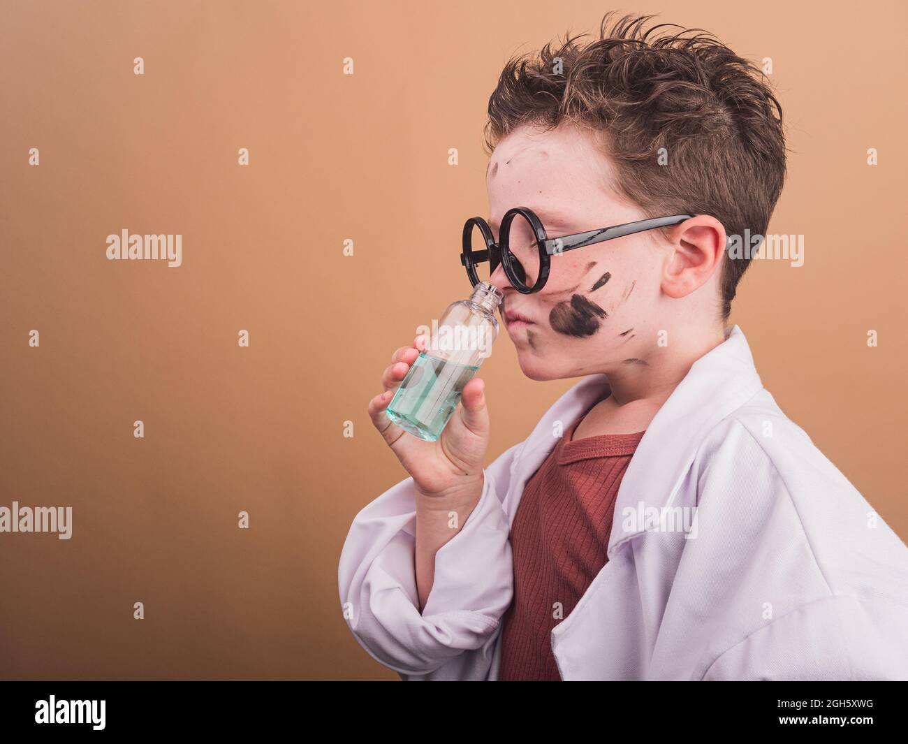 Chemist child in plastic glasses with paint spots on face smelling