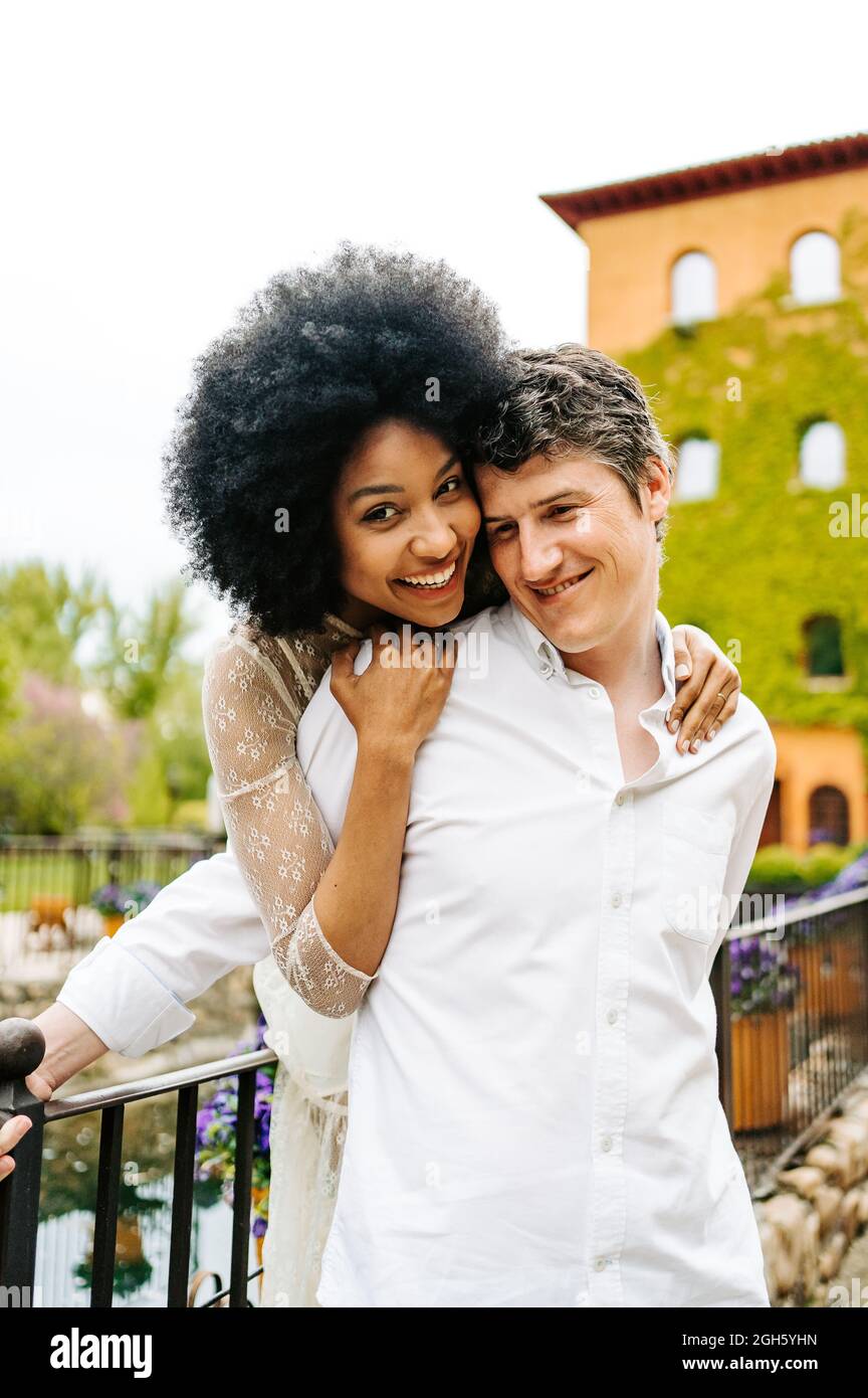 Loving black Woman with Afro hairstyle hugging smiling man from behind ...