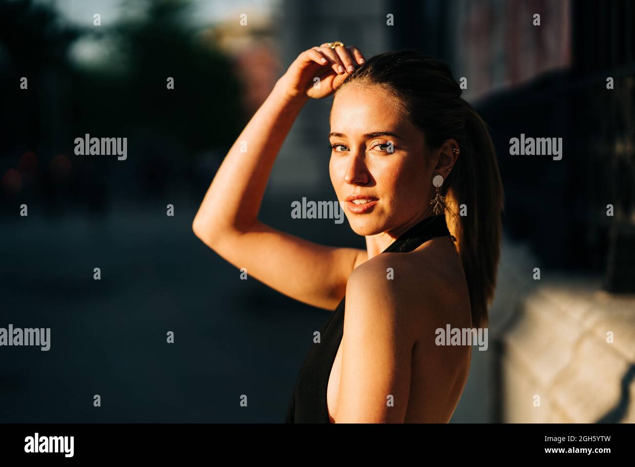 Pensive young female entrepreneur in eyeglasses touching chin with pen while standing with water bottle tablet and notebook and thinking about plans Stock Photo