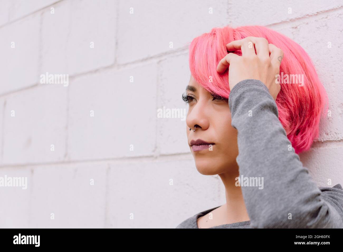 Pensive young female with dyed hair in casual clothes looking away ...