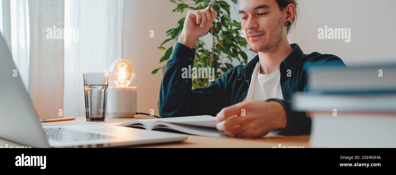 College student at campus while studying virtual learning for pass exam to university. Young man study using laptop in home. Wide image Stock Photo