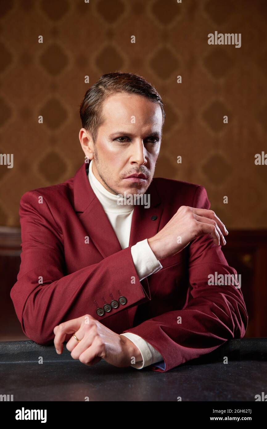 Serious pensive adult male theater artist with makeup and in elegant outfit looking away while thinking over decision Stock Photo