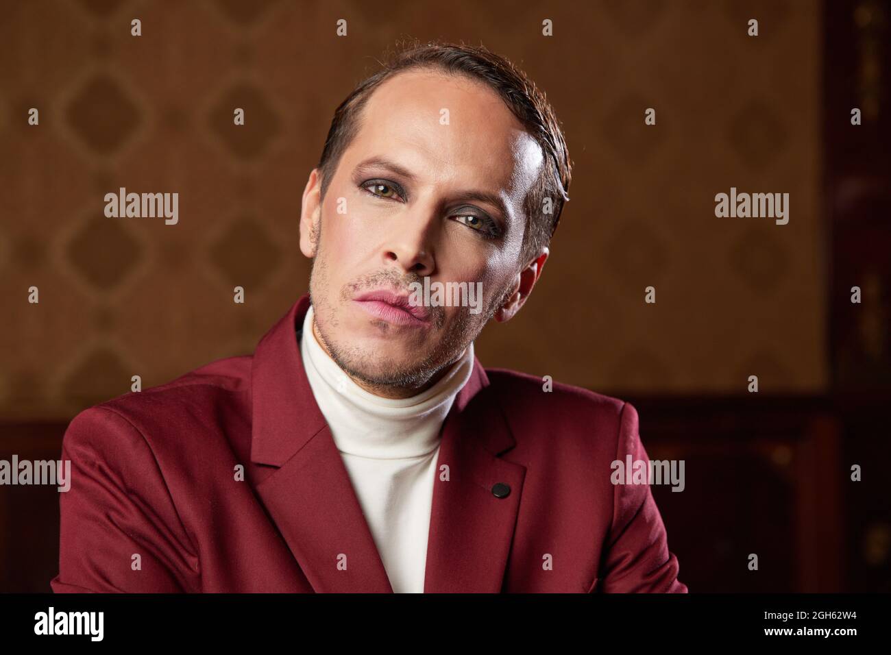 Serious pensive adult male theater artist with makeup and in elegant outfit looking at camera while thinking over decision Stock Photo