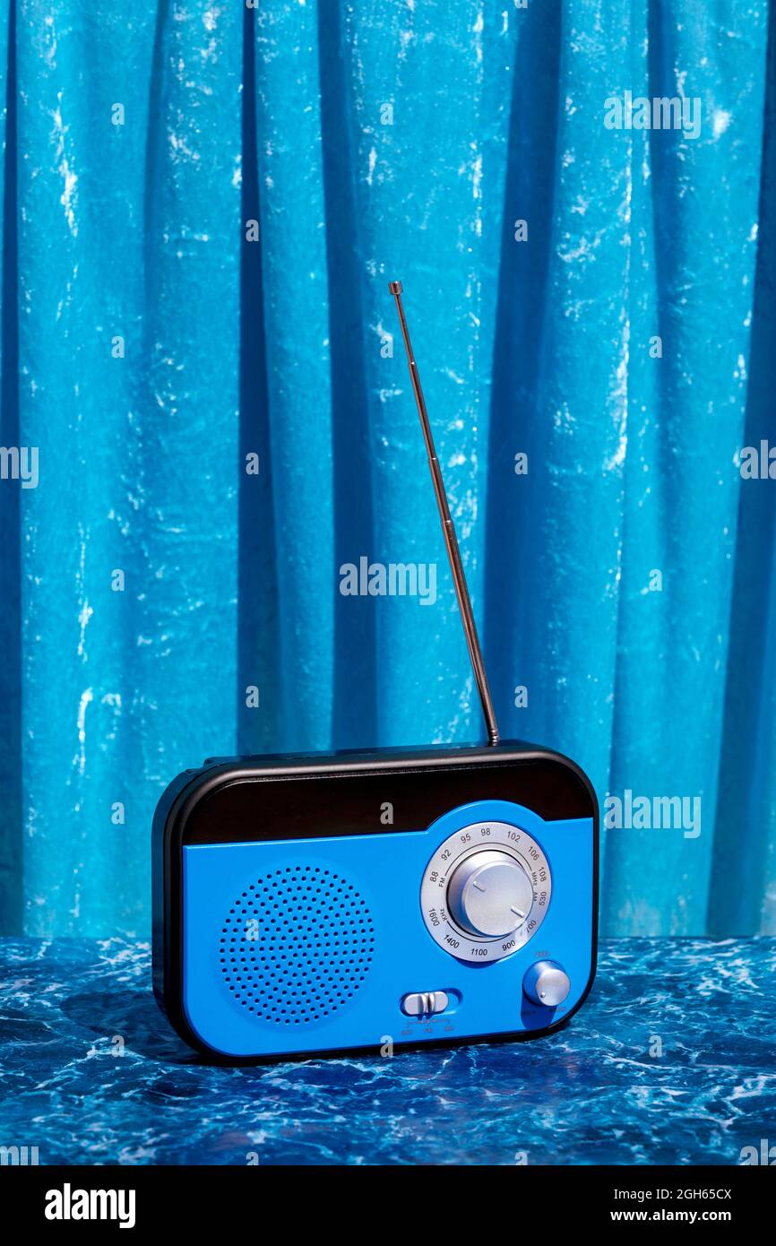Retro shiny radio receiver placed on marble table on blue background in studio Stock Photo