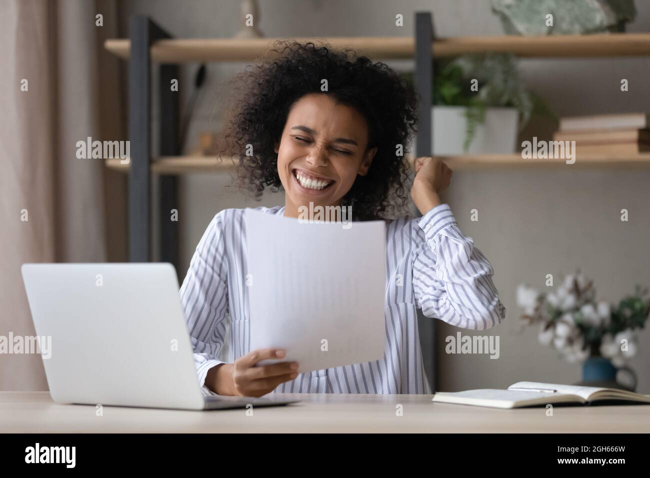 Cheerful african business lady read paper report with good news Stock Photo