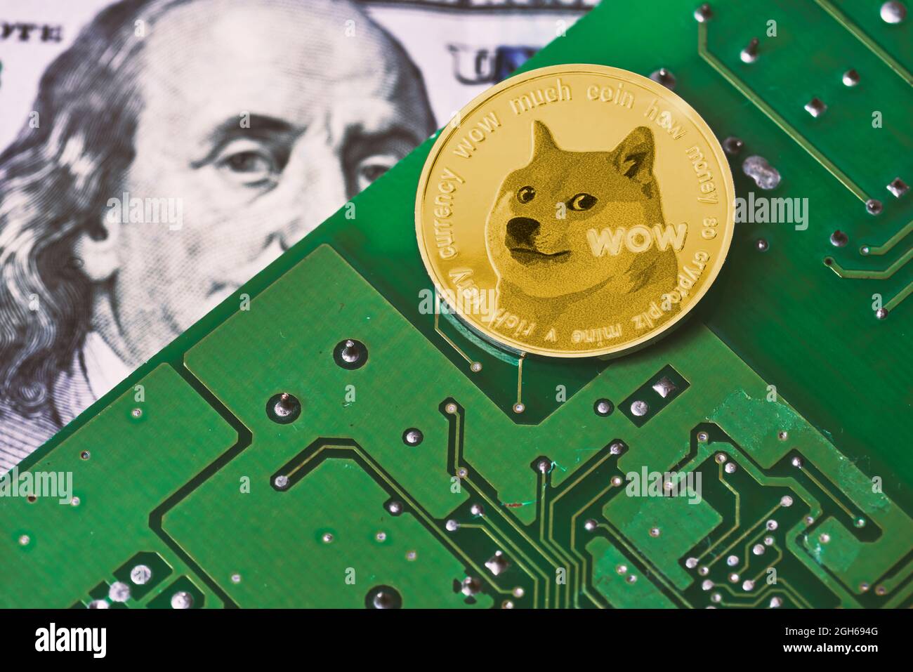 Dogecoin on computer motherboard surface and us dollar bill. US dollar banknote, printed circuit board and popular Dogecoin Stock Photo