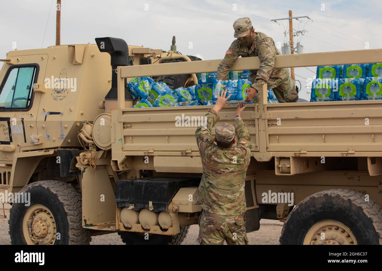 Spc. Patrick Padaong, top, hands a case of water to Spc. Michael Vasquez, both assigned to 1st Battalion, 6th Infantry Regiment, 2nd Brigade Combat Team, 1st Armored Division, as they continue to deliver water to drop points at Fort Bliss’ Doña Ana Complex in New Mexico, Sept. 4, 2021. The Department of Defense, through U.S. Northern Command, and in support of the Department of Homeland Security, is providing transportation, temporary housing, medical screening, and general support for at least 50,000 Afghan evacuees at suitable facilities, in permanent or temporary structures, as quickly as p Stock Photo