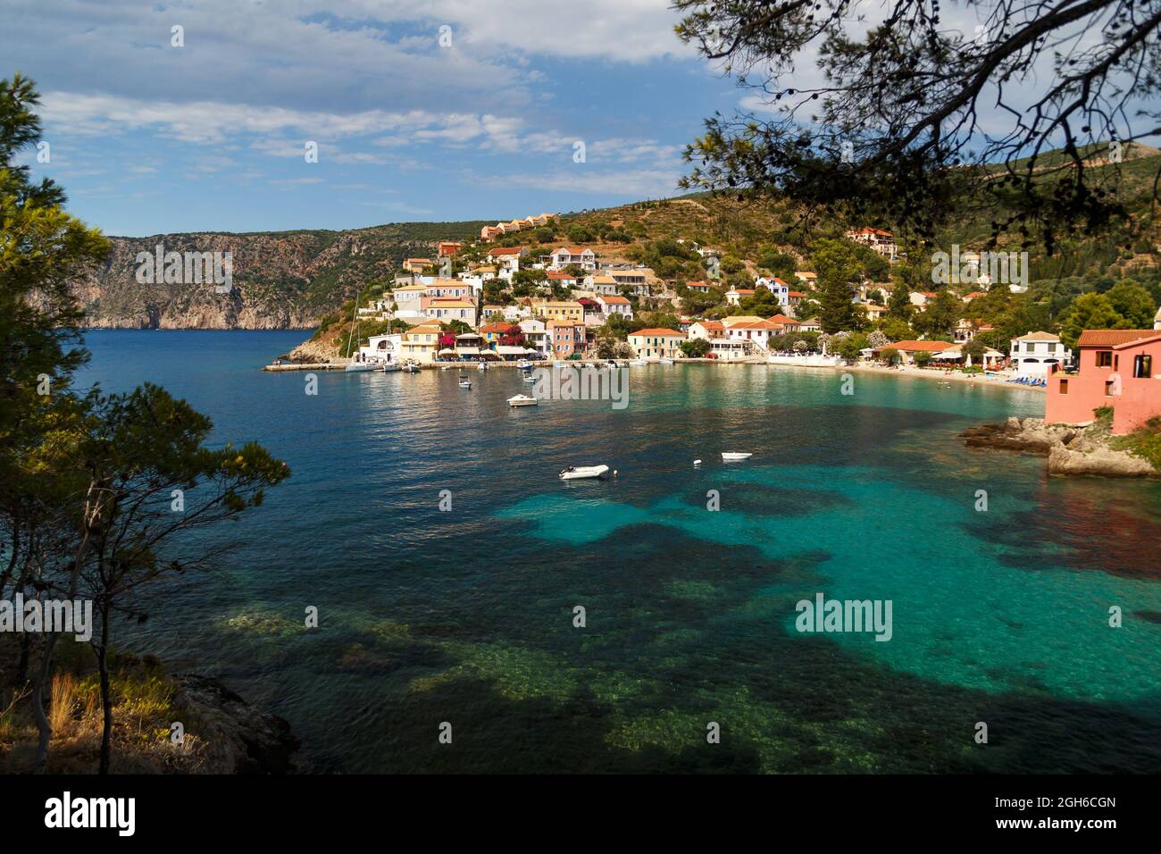 A view at green, blue bay, sea-front street of Asos village, greek colorful houses and turquoise Ionian Sea water. Summer scenery of famous travel destination in Europe. Stock Photo