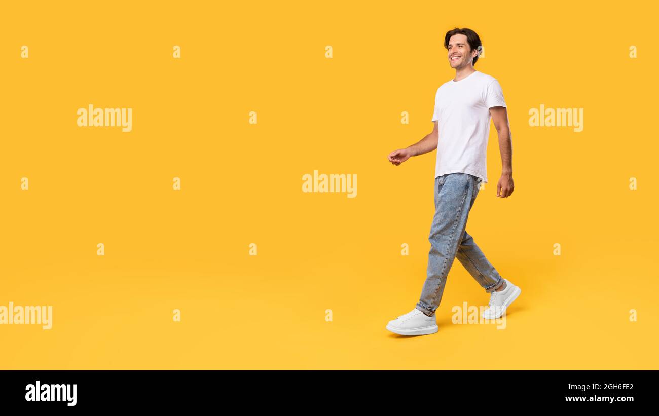 Young bearded man walking isolated on yellow background Stock Photo