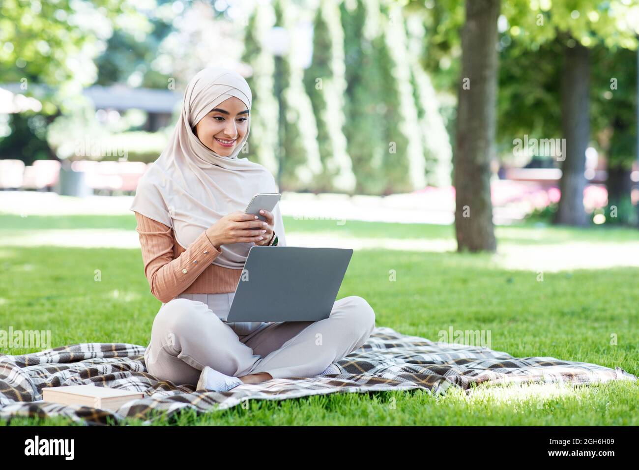 Happy pretty young islamic female in hijab with laptop chatting on ...