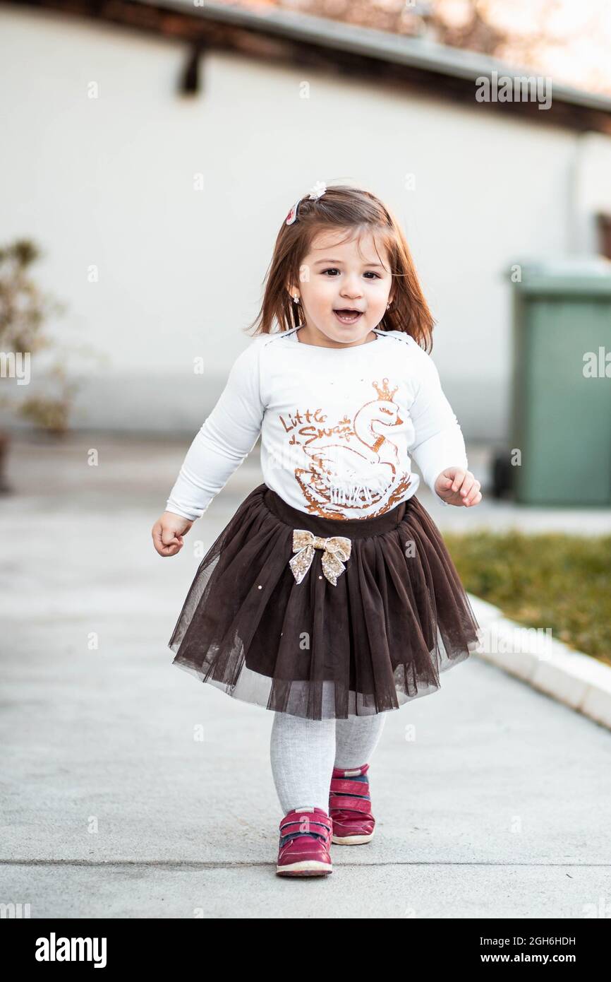Cute, little toddler girl walking outdoors and smiling Stock Photo