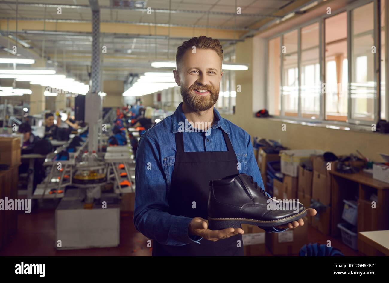 Male shoe factory worker shows one shoe from a new collection of