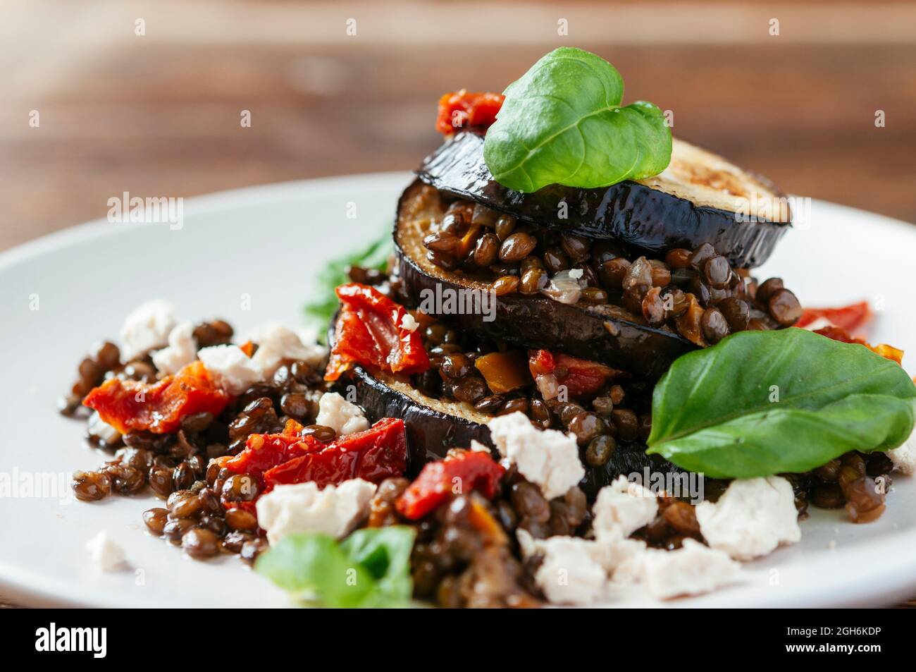 Eggplant lentil stacks with soy cheese, sun dried tomatoes and basil leaves. Stock Photo