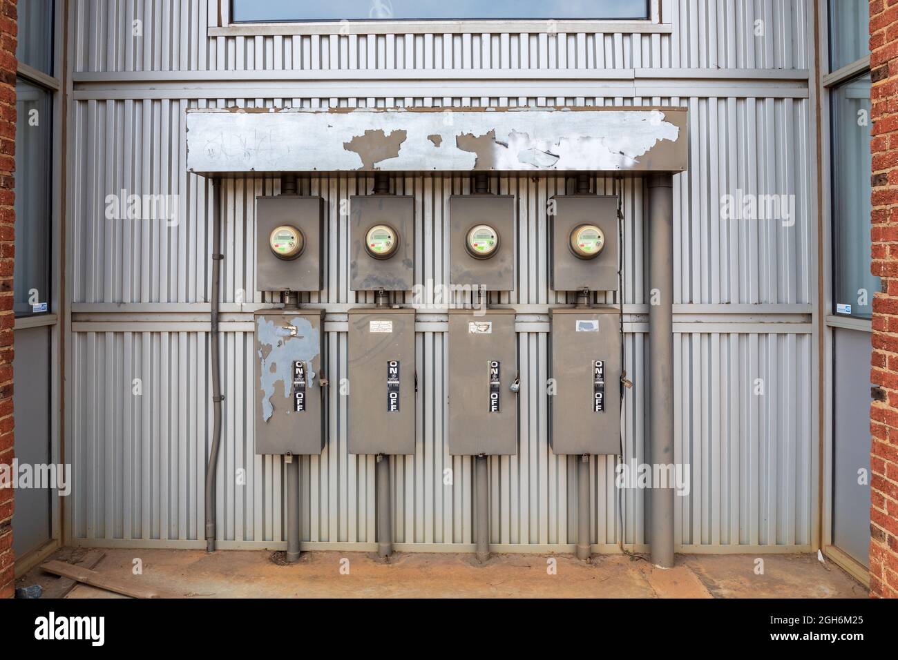 CHARLOTTE, NC, USA-25 JULY 2021: A wall of four electric power meters and boxes of breakers along with a master on/off switch. Stock Photo
