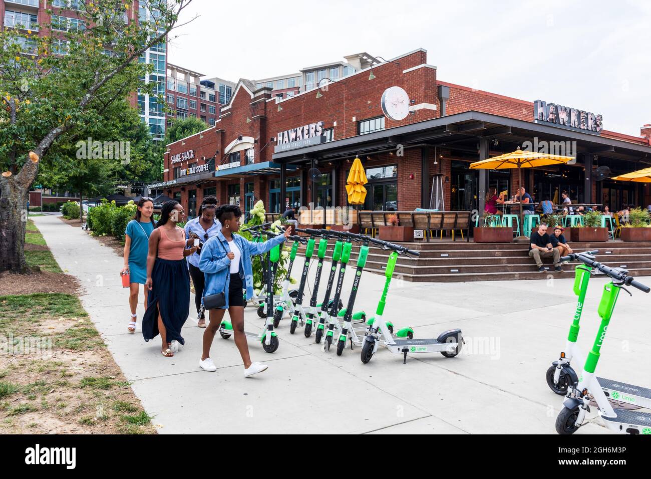 CHARLOTTE, NC, USA-25 JULY 2021: Group of four young women walking to Hawkers Asian Street Fare restaurant in South End, with people dining at outside Stock Photo