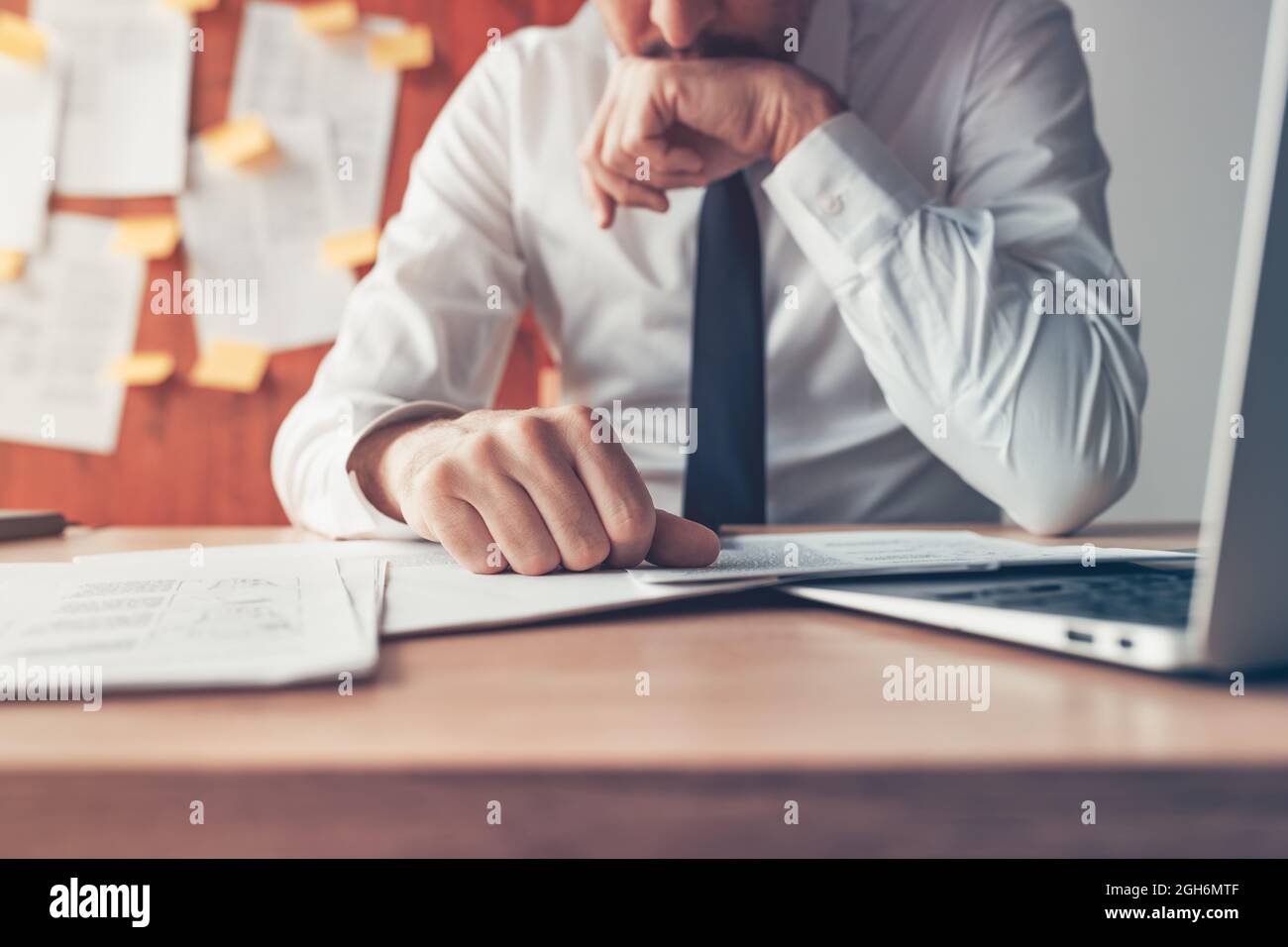 Worried businessman reading business report document at office desk, close up with selective focus Stock Photo
