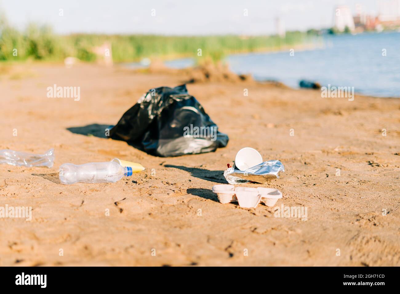 Trash on the beach. Used garbage, plastic wasted water bottle, coffee cup, highlighting the worldwide crisis of plastic pollution. Environment ecology Stock Photo