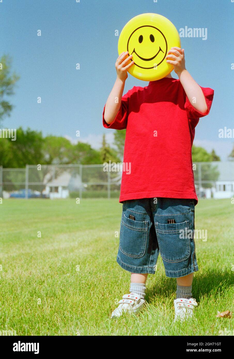 Small child with happy yellow frisbee in park setting. Stock Photo