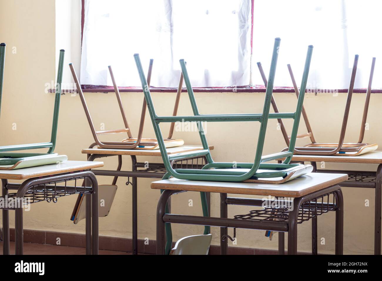 Photo of some chairs on tables in a classroom in a primary school.The photo is taken in horizontal format. Stock Photo
