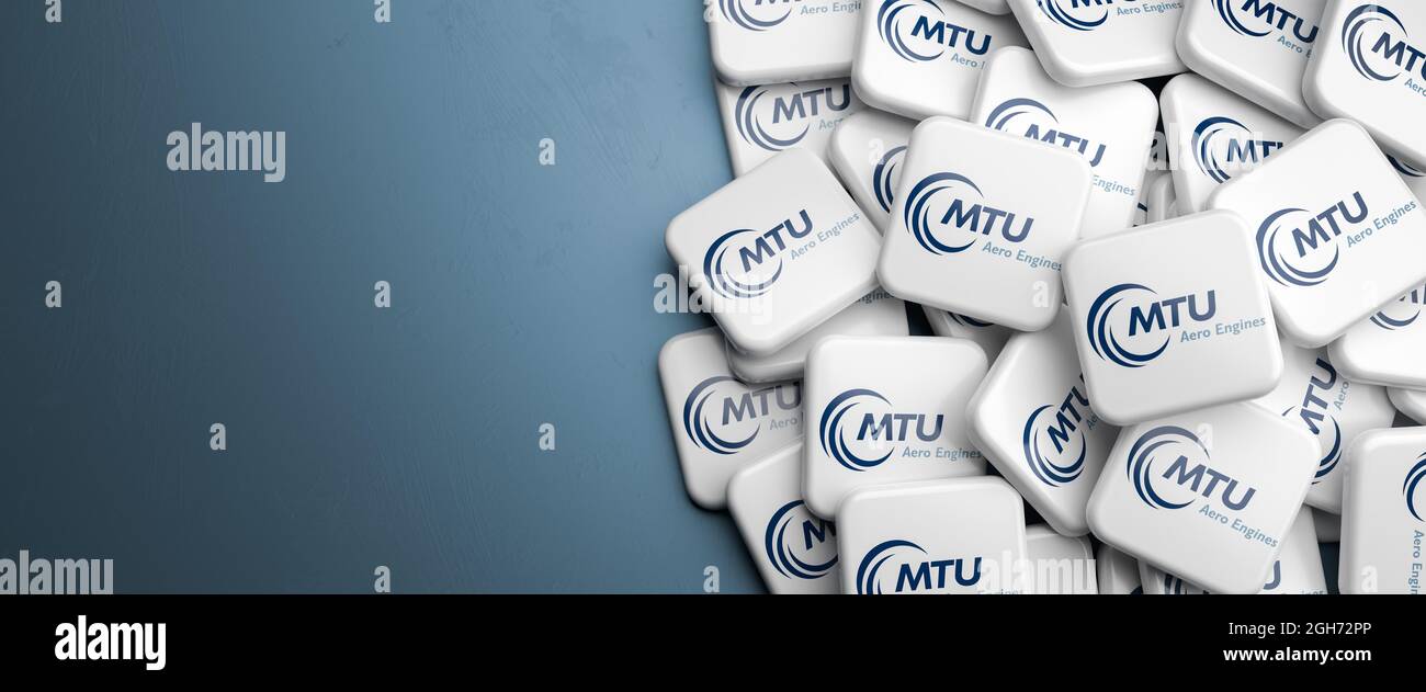 Logos of the German aircraft engine manufacturer MTU aero engines on a heap on a table. Copy space. Web banner format. Stock Photo