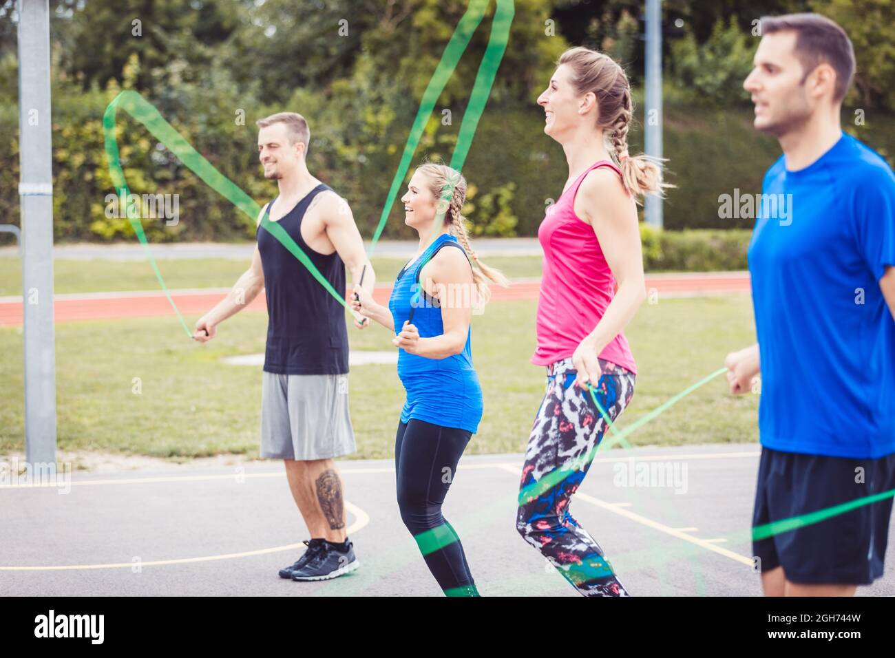 Four people practicing rope skipping in field Stock Photo